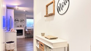 Une cuisine moderne avec un plan de travail blanc, un miroir encadré d’osier et un panneau mural sur lequel on peut lire le mot « Moi ».