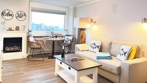 Un salon moderne avec une cheminée, un coin repas et un canapé agrémenté de coussins décoratifs.