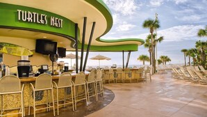Un restaurante llamado "Turtles Nest" con terraza, una barra y vistas a la playa.