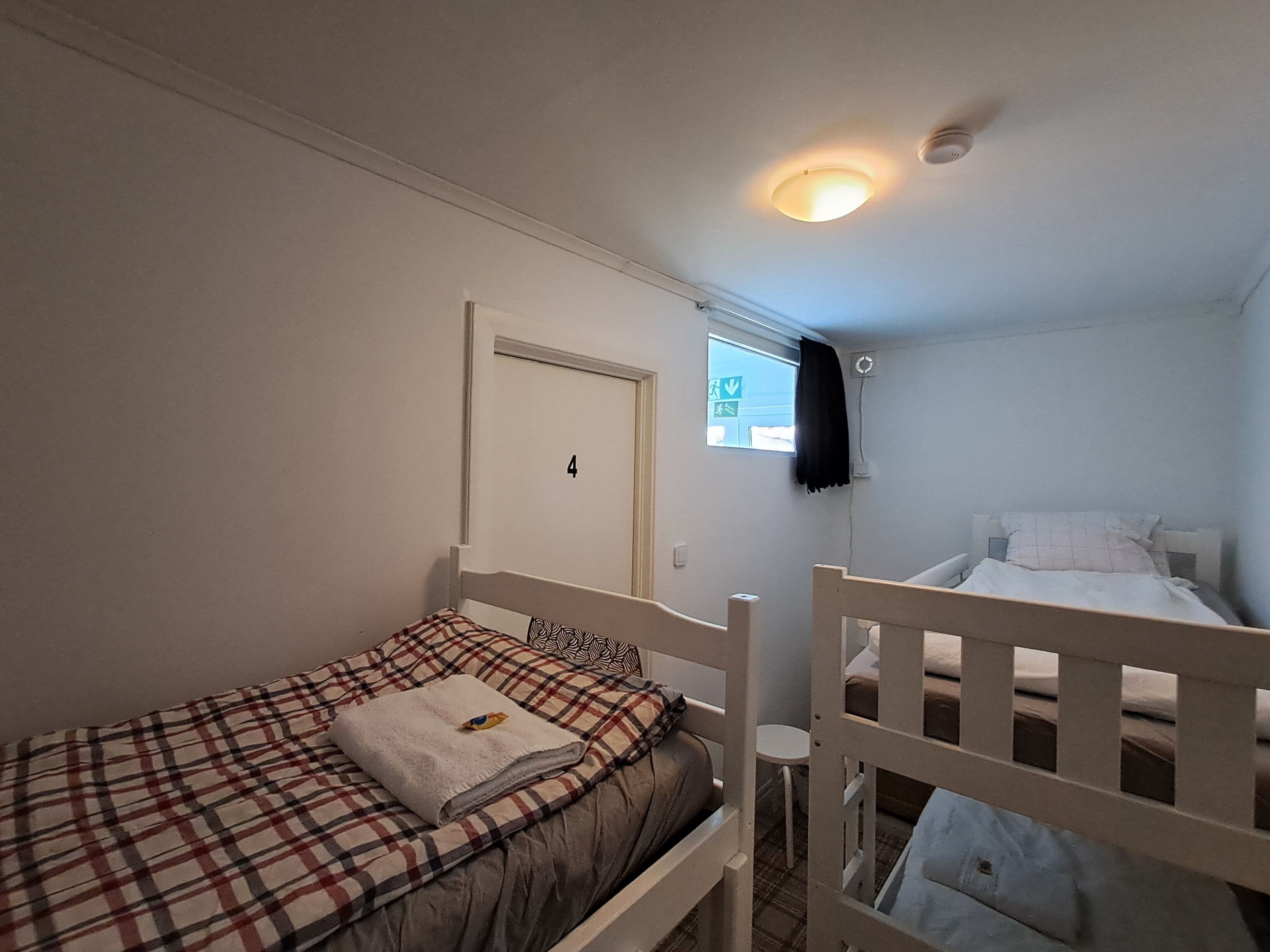 A small, single-room accommodation with a bunk bed and a single bed.