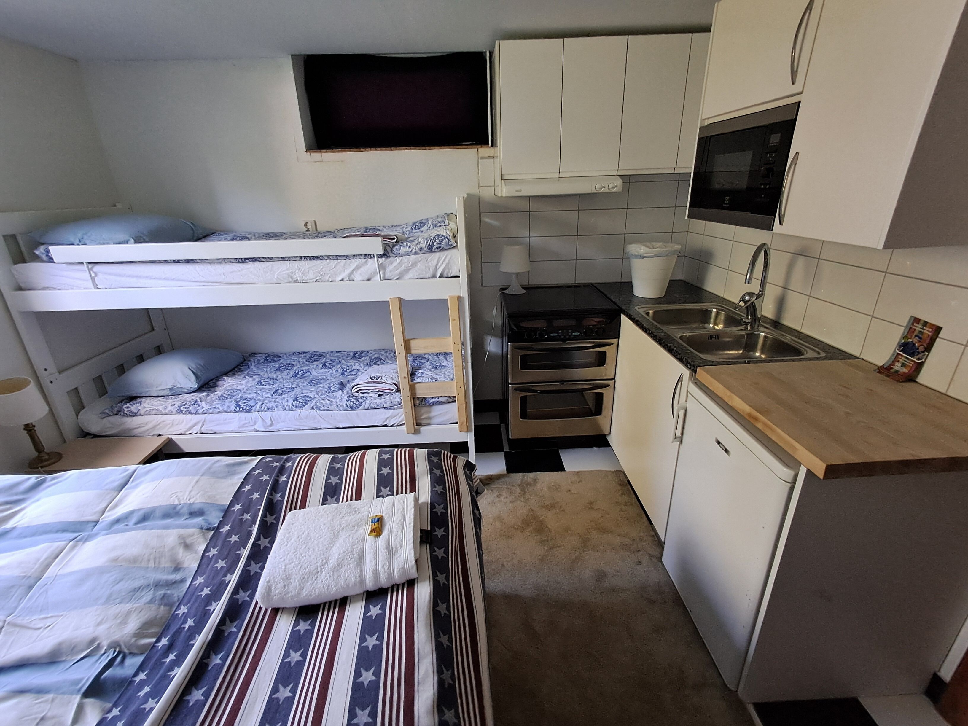A compact room with bunk beds, a kitchenette, and a small TV.