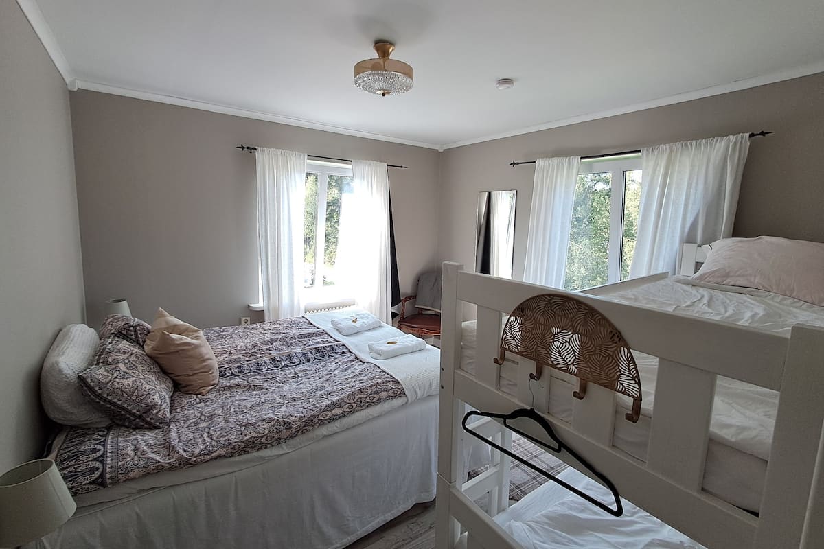 Un dormitorio con dos camas, un ventilador de techo y una ventana con cortinas.