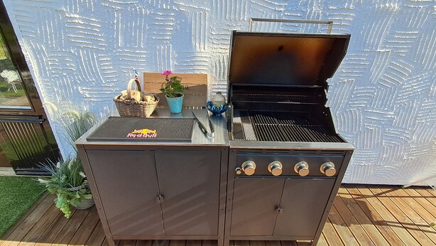 A barbecue grill with a built-in sink and storage cabinets, set on a wooden deck. - Ankis Bed and Breakfast (Storebro)