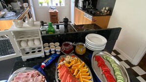 A buffet spread with various foods including ham, cheese, watermelon, oranges, and cucumber slices. - Ankis Bed and Breakfast (Storebro)