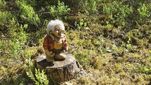 A sculpture of a figure sitting on a tree stump surrounded by greenery. - Ankis Bed and Breakfast (Storebro)