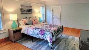 Une chambre à coucher avec un lit, des tables de chevet, une fenêtre et une porte.