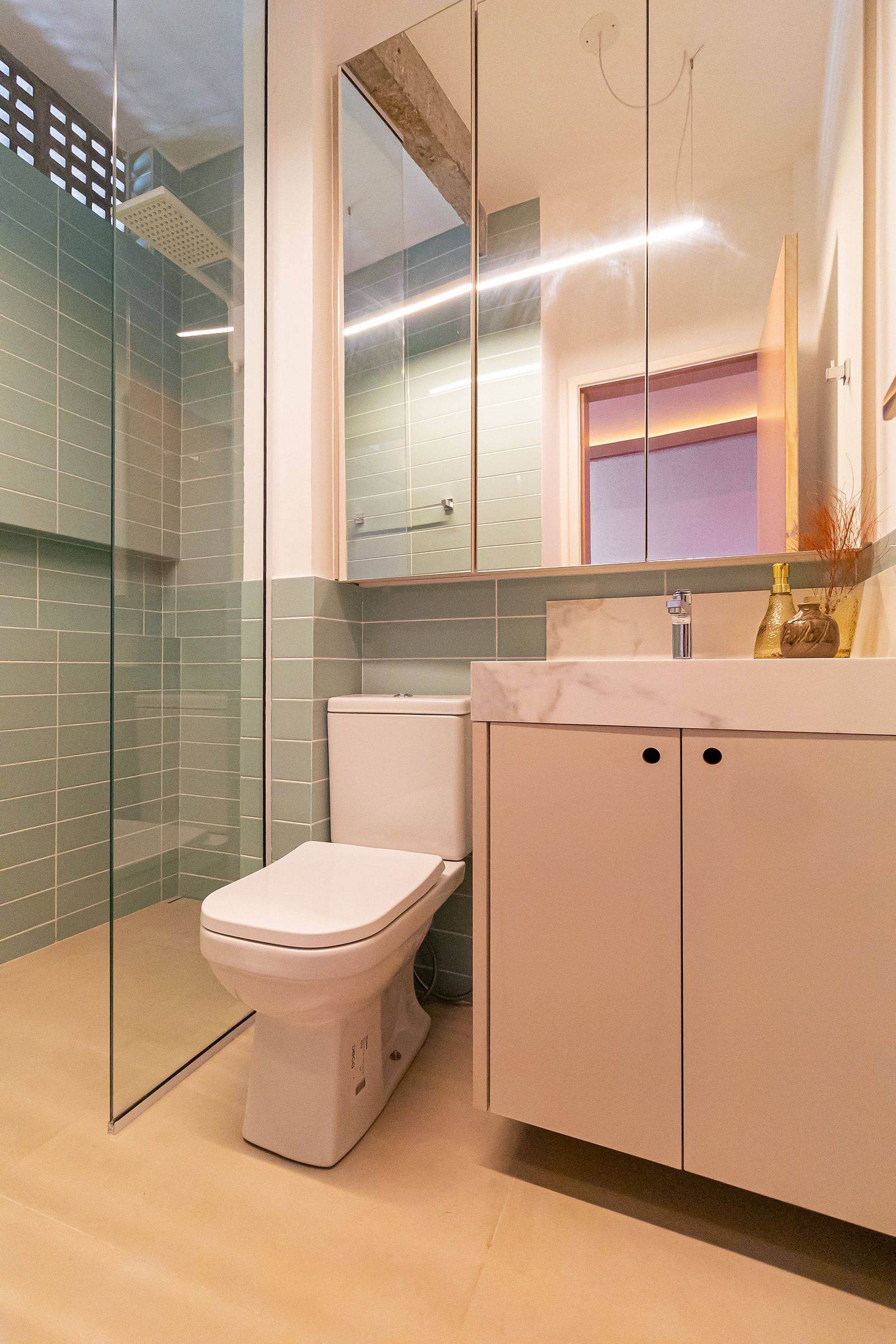 A modern bathroom with a glass shower enclosure, a white toilet, and a marble sink with a mirror above.