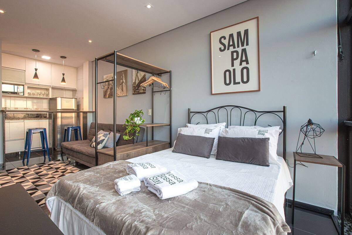 A modern hotel room with a bed, a desk, a wardrobe, and a bathroom.