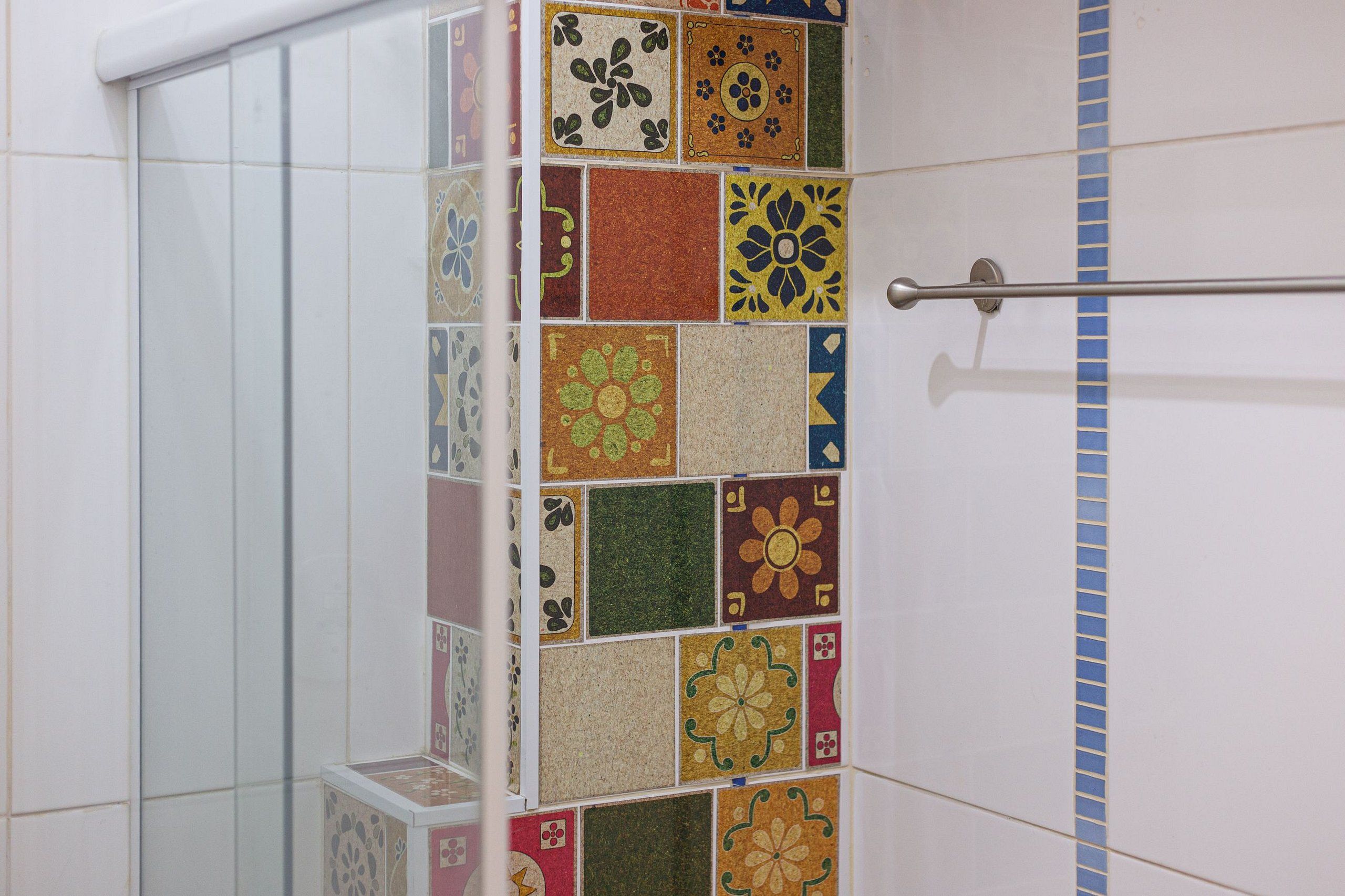 Un área de ducha con pared de azulejos con diversos diseños y colores.