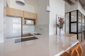 Une cuisine moderne dotée d’un grand îlot central, de meubles en bois, d’un réfrigérateur, d’un four à micro-ondes et d’un vase rempli de fleurs.