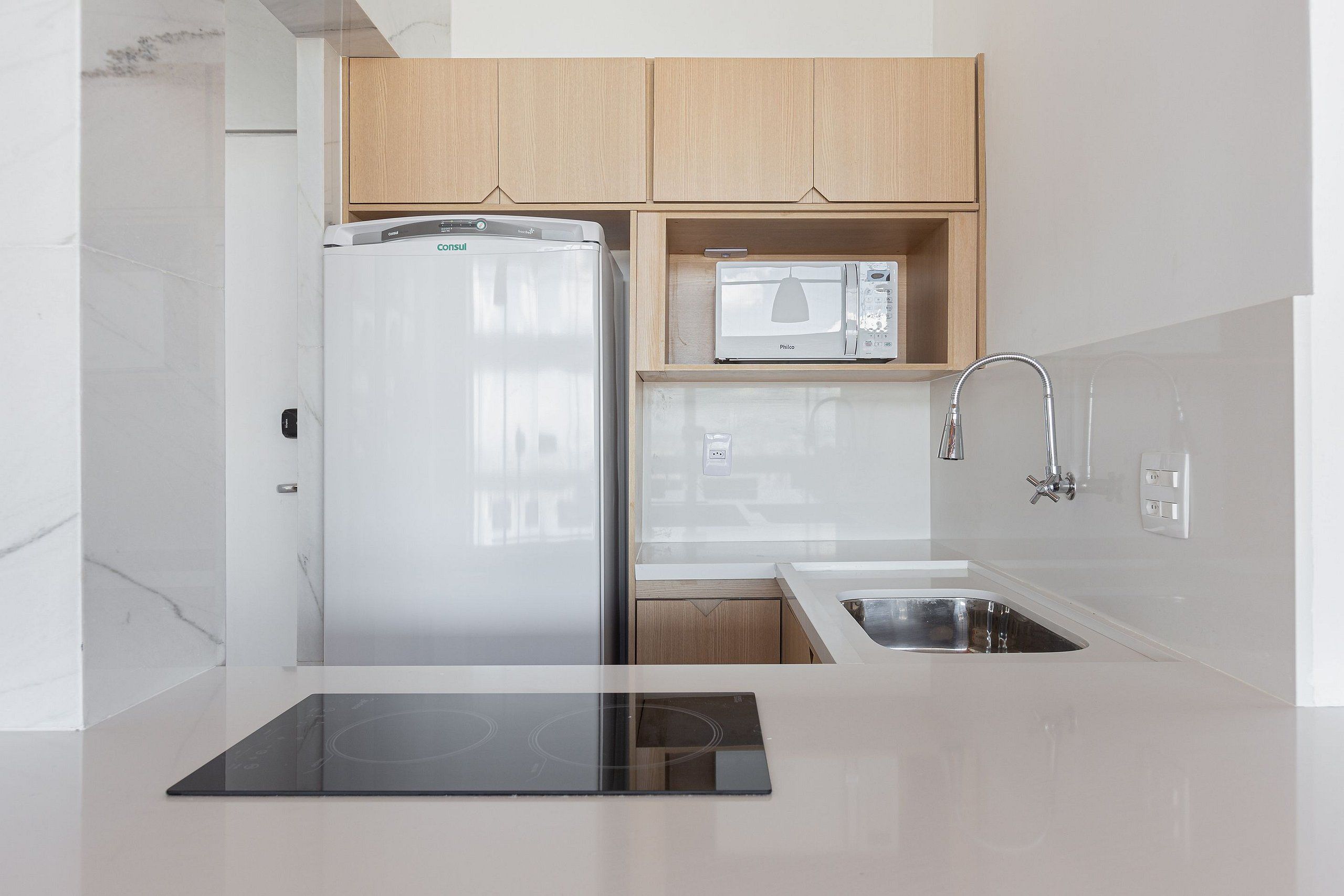 A modern kitchen with a built-in refrigerator, microwave, and stainless steel sink.