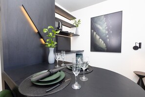 Een moderne eetruimte met een donker houten tafel, groene borden en heldere wijnglazen.