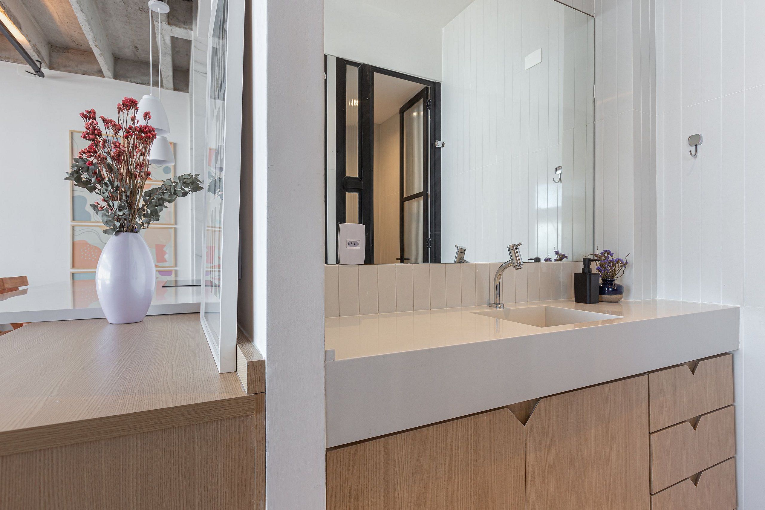 A modern bathroom with a large mirror, a sink, and wooden cabinetry.