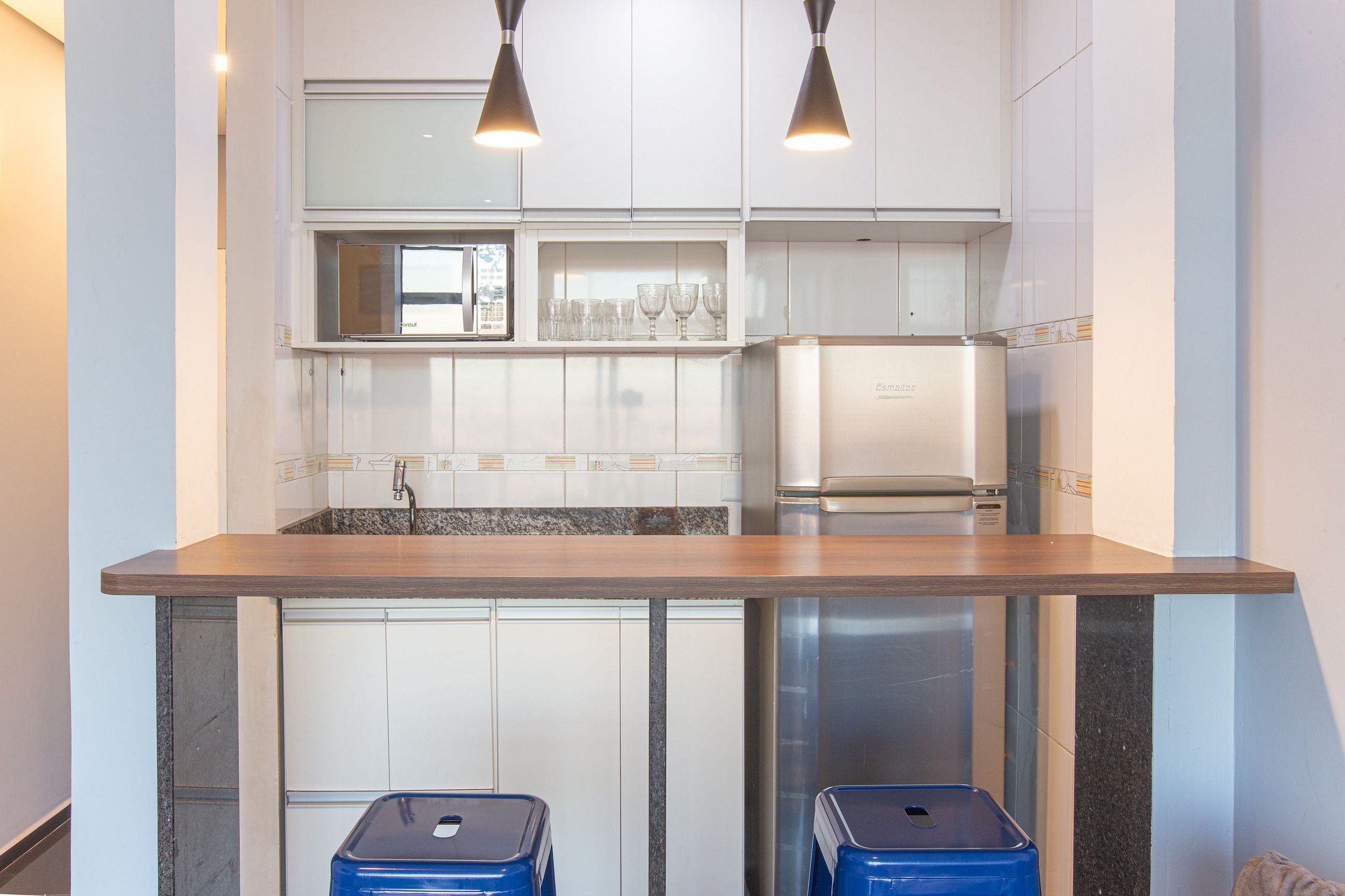 Eine moderne Küche mit weißen Schränken, einer Arbeitsplatte aus Granit, einem Edelstahl-Kühlschrank und zwei blauen Mülleimern.