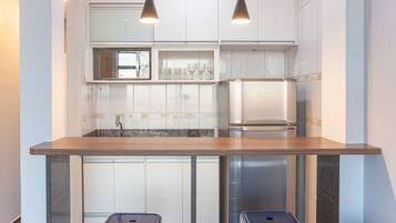 Eine moderne Küche mit weißen Schränken, einer Arbeitsplatte aus Granit, einem Edelstahl-Kühlschrank und zwei blauen Mülleimern.