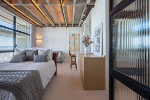 Quarto moderno com uma cama grande, uma escrivaninha e vista para a cidade.