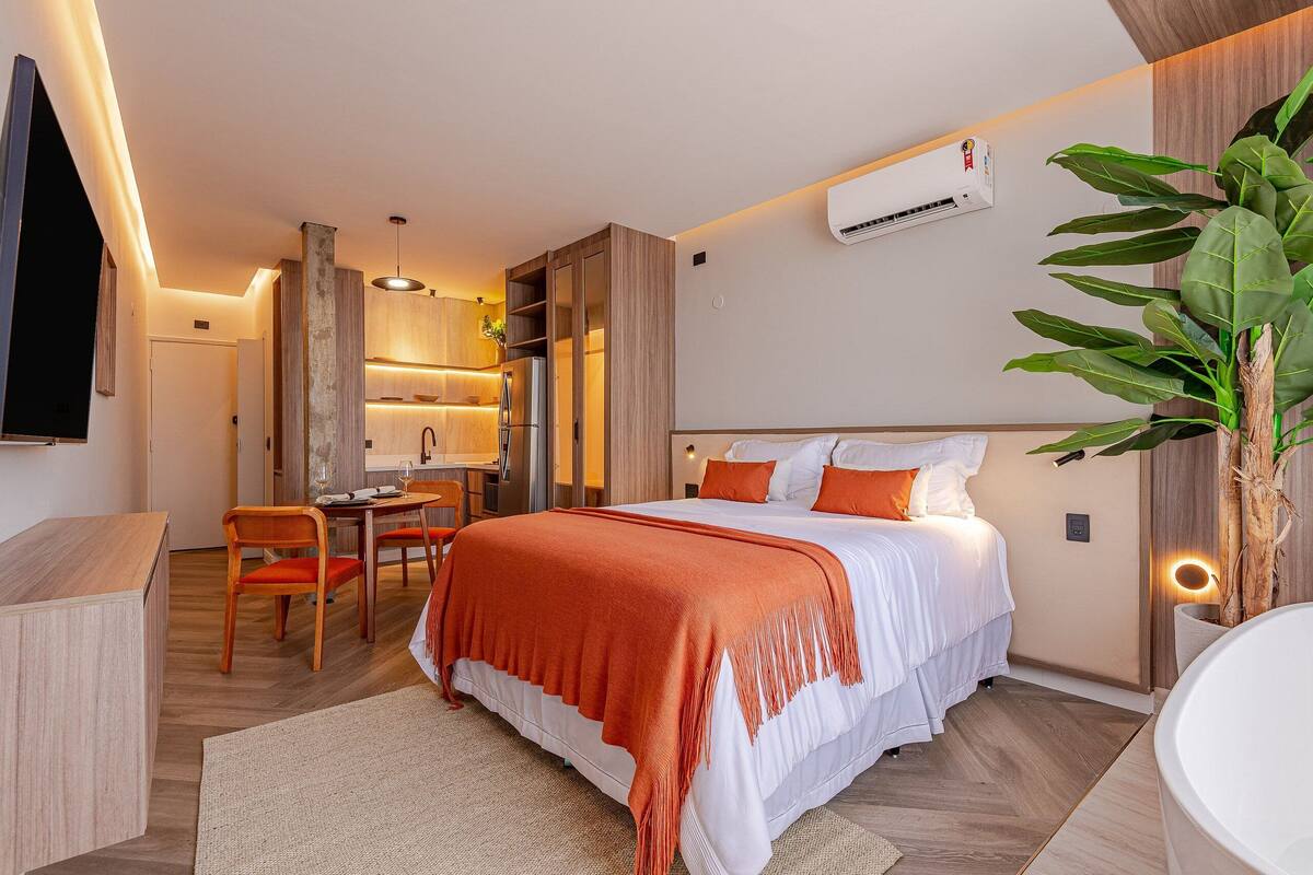 A modern hotel room with a bed, a desk, and a bathroom.