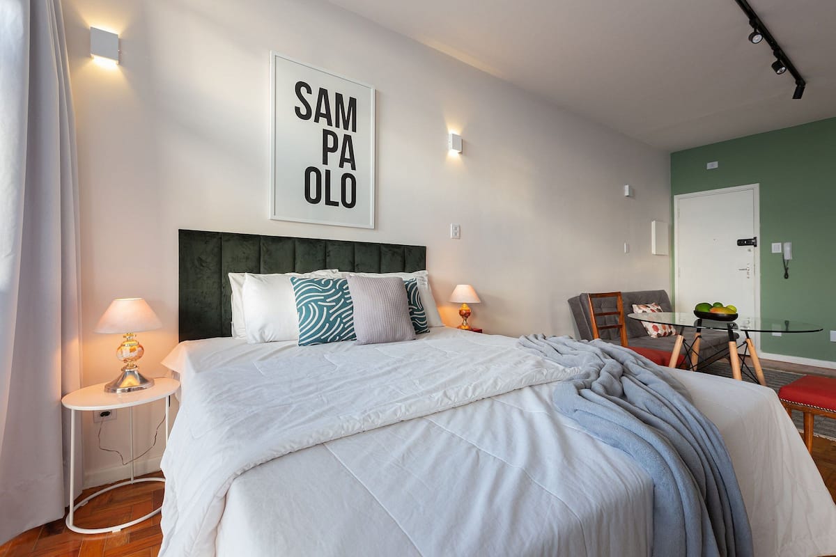 A neatly arranged bedroom with a large bed, two bedside tables with lamps, a chair, and a table with fruit.