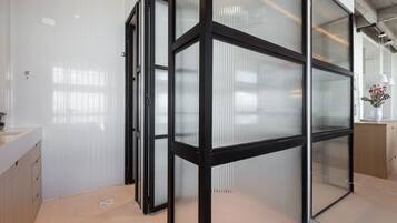 Ein modernes Interieur mit einer Glassturzwand, einem Holzschrank und einem weißen Waschbecken.