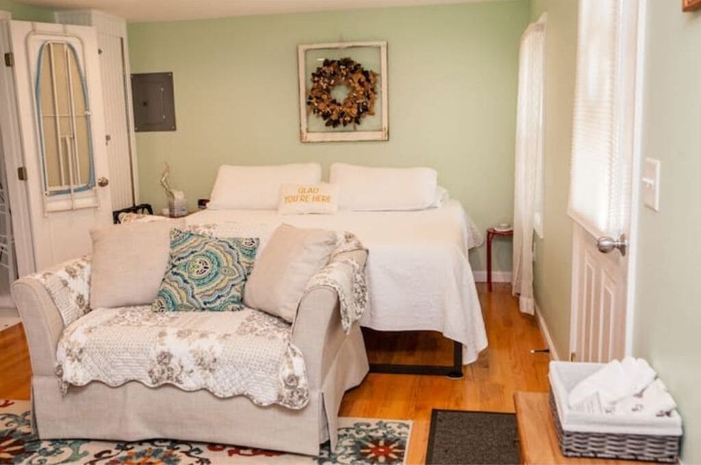 A cozy bedroom with two beds, a sofa, and a decorative wreath on the wall.