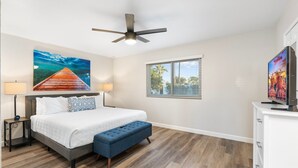 A bedroom with a bed, a ceiling fan, a window with blinds, a TV, and a painting on the wall. - PuttPutt, Pickleball, Basketball, Ping Pong & Game Room! Pool & Spa! (Scottsdale)