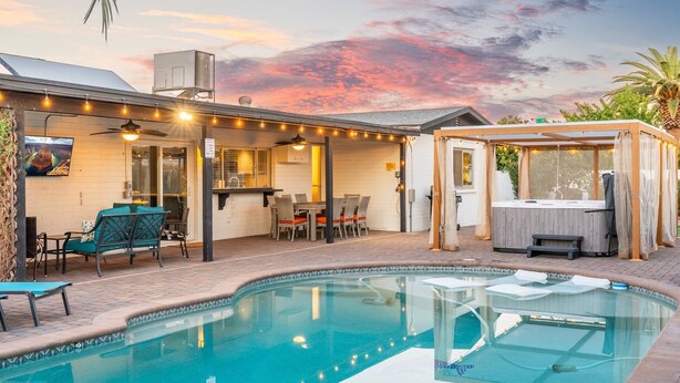 A backyard with a swimming pool, outdoor seating, a hot tub, and string lights. - PuttPutt, Pickleball, Basketball, Ping Pong & Game Room! Pool & Spa! (Scottsdale)