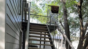 A concrete staircase leading to a building with a metal railing and a tree nearby.