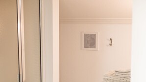 A bathroom with a shower, toilet, and a stack of towels on a radiator.