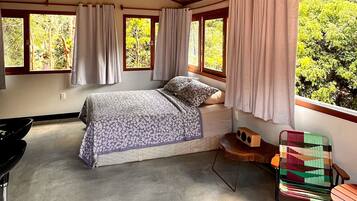 A bedroom with a bed, a chair, a window, and a ceiling fan.