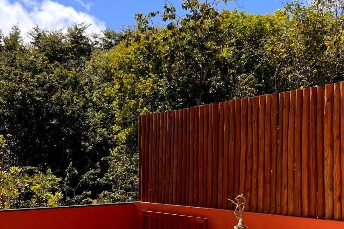 A wooden deck with a hot tub, outdoor seating, and a wooden wall.