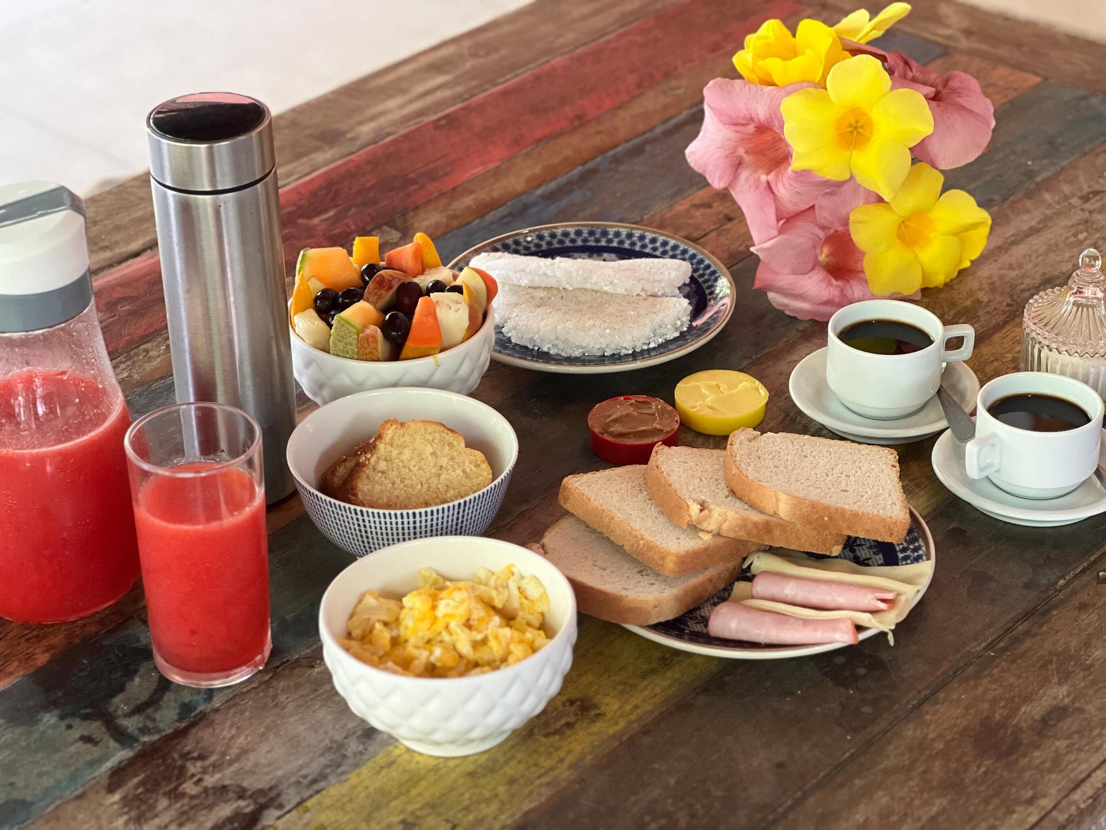 A breakfast table with various food items, including fruits, bread, eggs, and beverages.