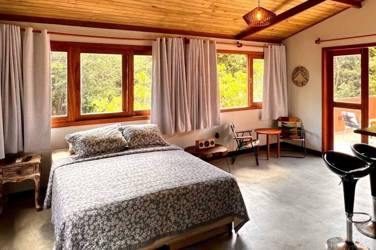 A bedroom with a large bed, a desk, two chairs, and a ceiling fan.