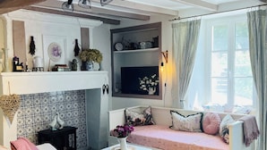 Uma sala de estar aconchegante, com um sofá, uma mesinha e uma estante decorativa.