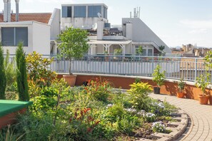 A rooftop garden with potted plants and a metal railing.