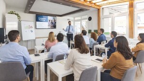Ein Konferenzraum mit Präsentationsbildschirm, Holzbalkendecke und einer Whiteboard-Tafel.