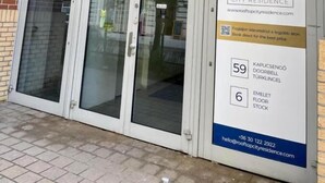 Ein Gebäudeeingang mit einem großen 'D'-Schild, Glastüren und einem Schild, das Rooftop City Residence mit Kontaktinformationen bewirbt.