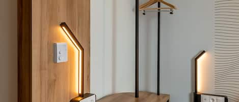 Una habitación moderna con un revestimiento de pared de madera, un perchero y dos lámparas fijadas a la pared.