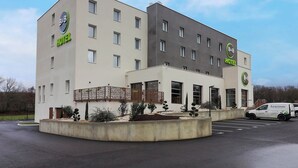 Hotel tipo bed and breakfast com design moderno, apresentando entrada central, várias janelas e área de estacionamento.