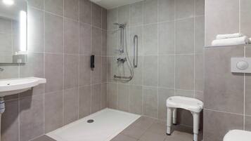 A modern bathroom with a shower, sink, toilet, and a small bench.