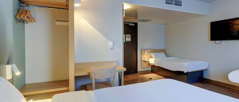 A hotel room with two beds, a desk, a chair, a TV, and a wardrobe.