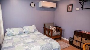 A bedroom with a bed, a chair, a dresser, and an air conditioning unit. - Cabin in the heart of the Hudson Valley, Cabin 4 (Newburgh)