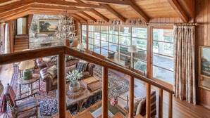 Un loft amplio con techo alto, chimenea de piedra, ventanas grandes y una zona de estar acogedora con vistas al exterior.