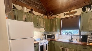 A kitchen with green cabinets, a white refrigerator, a stove, a microwave, and a sink. - Perfect Cabin 5 minutes to Blanchard Springs Nat. Park (Mountain View)