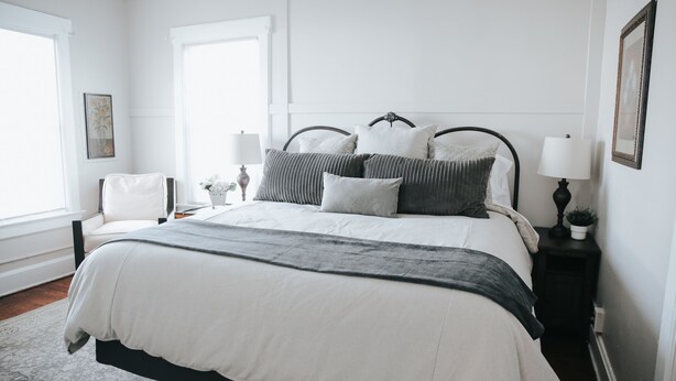 A bedroom with a large bed, a bedside table with a lamp, and a chair.
