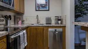 Una cucina moderna con mobili in legno, elettrodomestici in acciaio inossidabile, una macchina per il caffè e un'opera d'arte incorniciata al muro.
