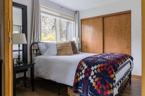 A bedroom with a bed, a nightstand, a lamp, a window with curtains, and a wardrobe. - McCall Suite Spot: 1-bedroom with indoor fireplace (McCall)
