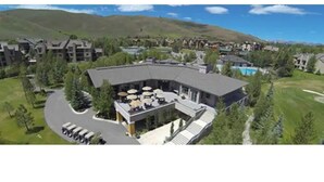 Um resort com piscina, área de estar externa e montanhas ao fundo.