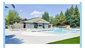 Um edifício com piscina, rodeado por árvores e céu claro.