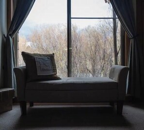 Relax in comfort with a sofa in front of a large window overlooking a wooded area.