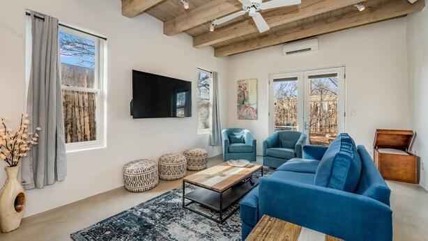 A modern living room with a blue sofa, a wooden coffee table, and a ceiling fan. - The Downtown Velvet Adobe (Santa Fe)